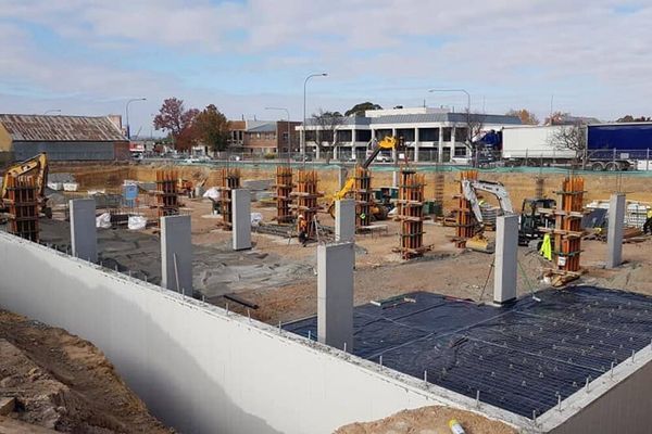 A construction site with a lot of concrete pillars and a building in the background.