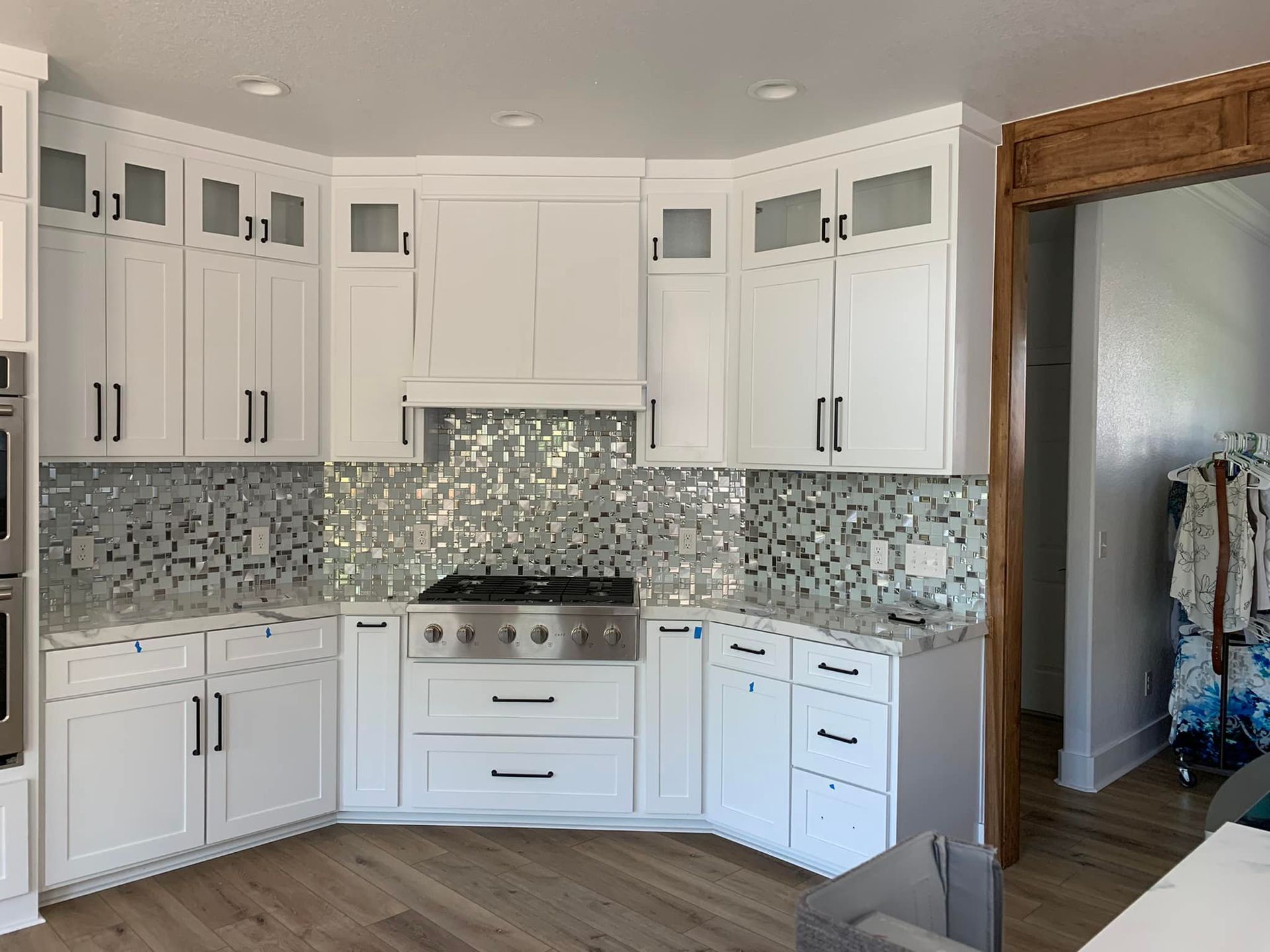 A kitchen with white cabinets and a stove top oven.