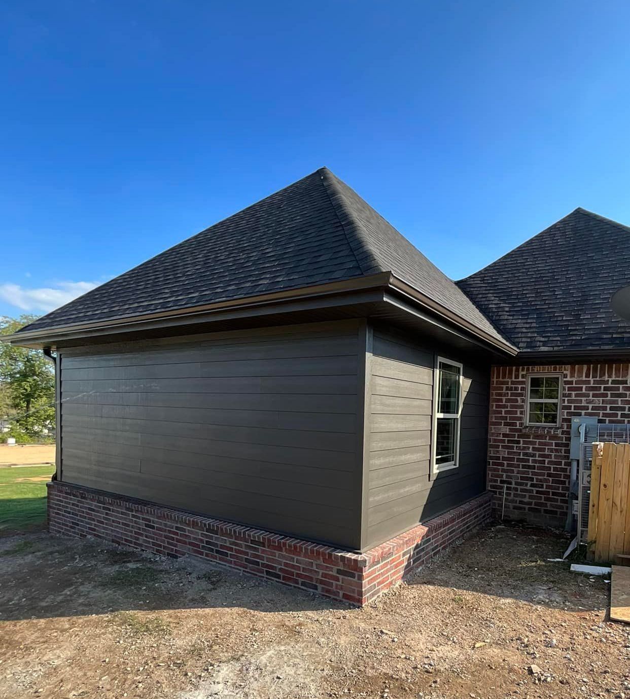 A house with a black siding and a black roof is being built.