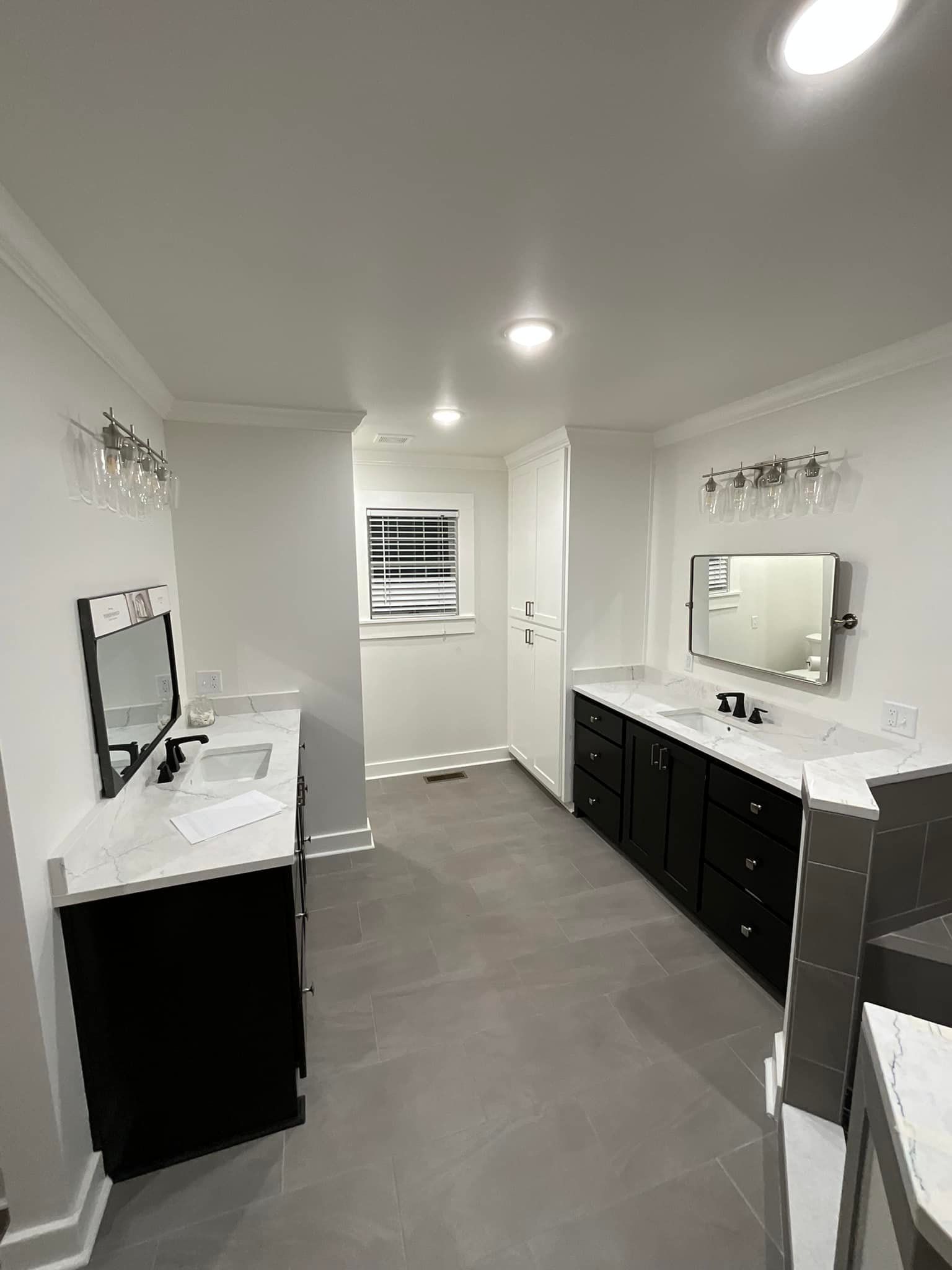 A bathroom with two sinks , a mirror and a window.