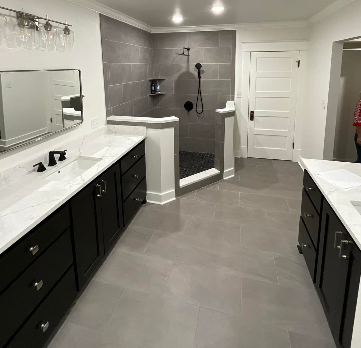 A bathroom with two sinks and a walk in shower.