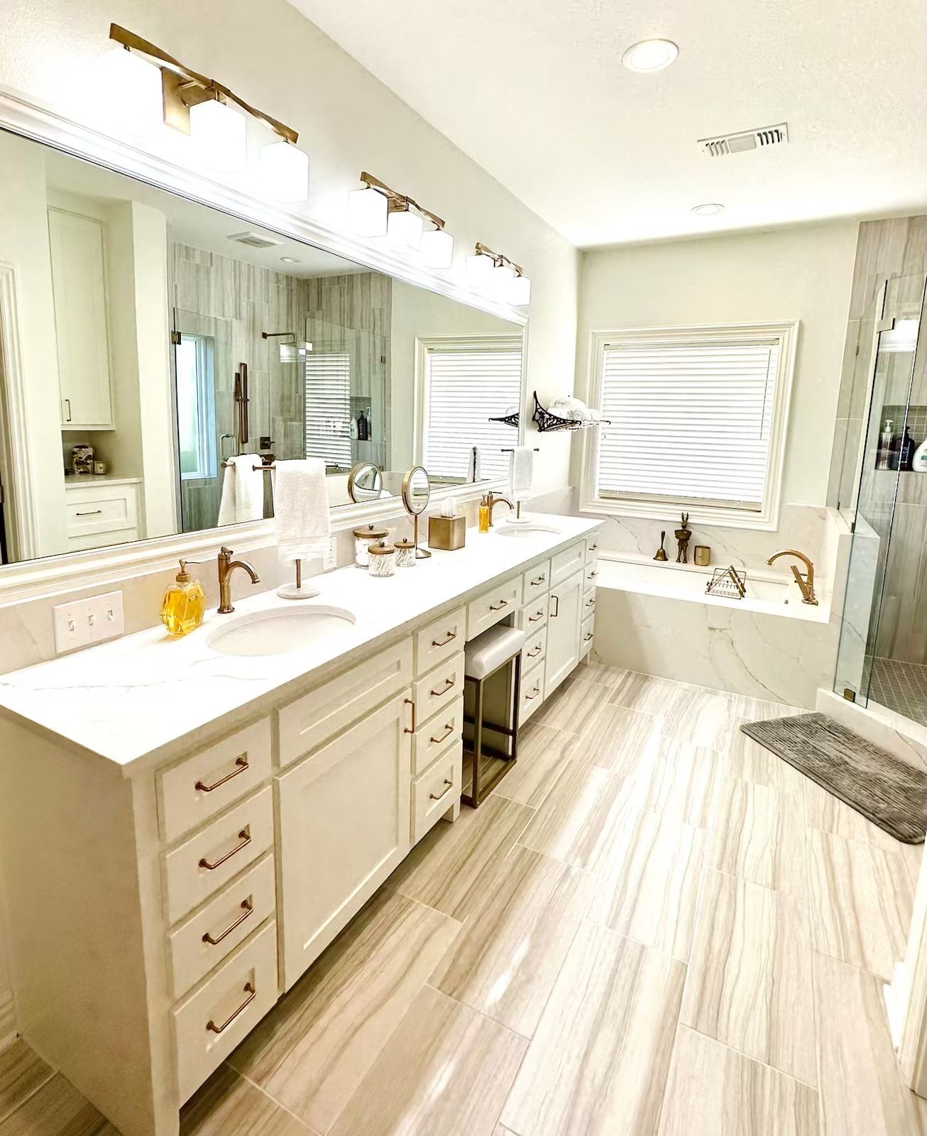 A bathroom with two sinks , a tub , and a large mirror.
