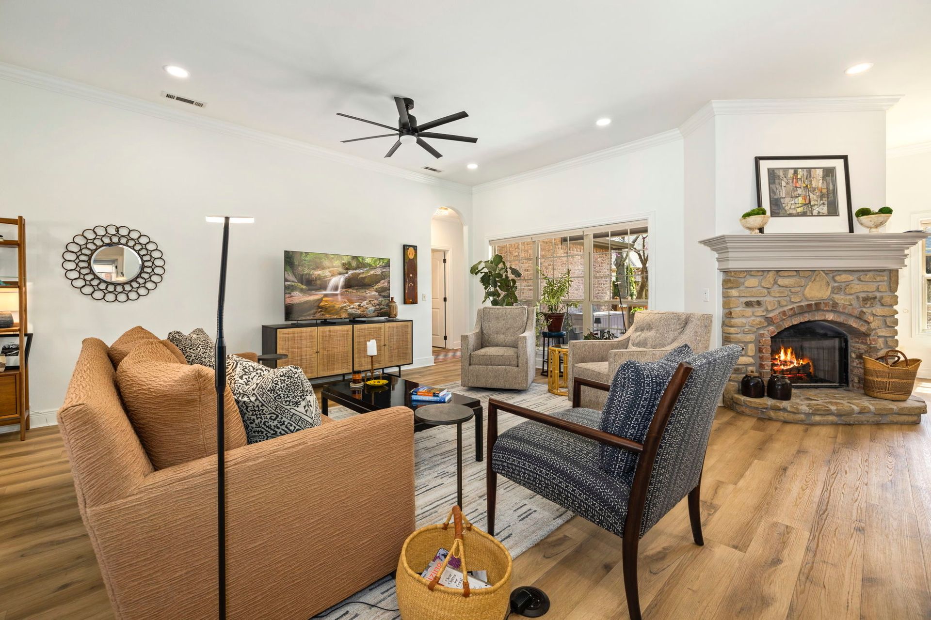An empty living room with a stone fireplace and sliding glass doors.