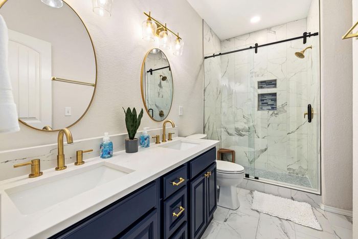 A bathroom with two sinks , a toilet , and a walk in shower.