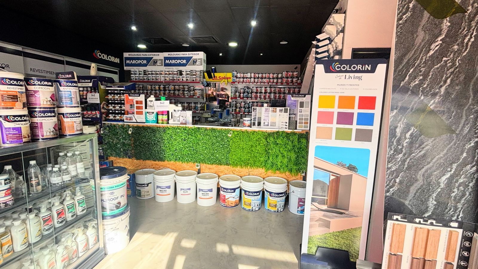 Interior de una tienda de pinturas, que muestra un mostrador con latas de pintura, muestras de color y diversos suministros.