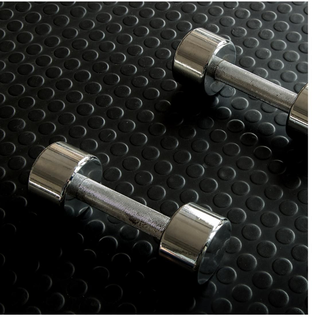 Suelo de caucho negro con rejilla de círculos empotrados.