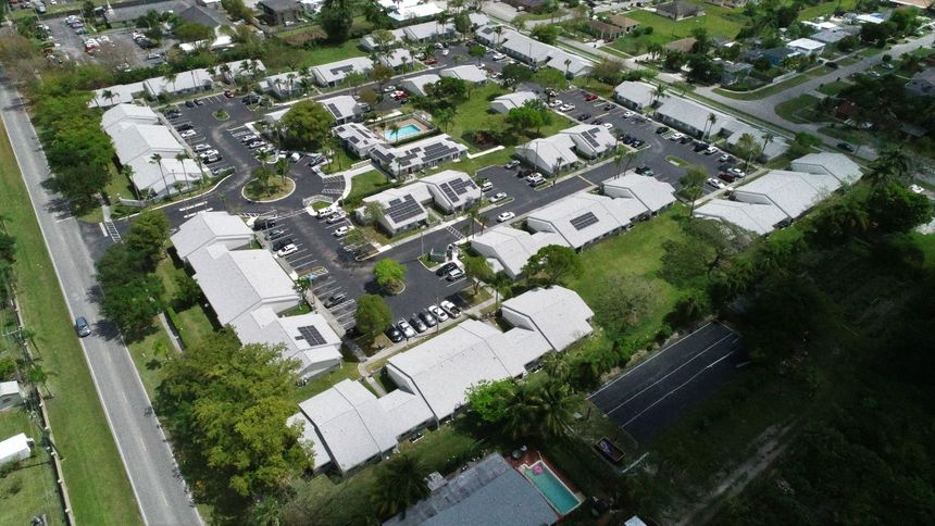 Aerial view of a residential neighborhood with multi-unit buildings, parking areas, and green spaces.