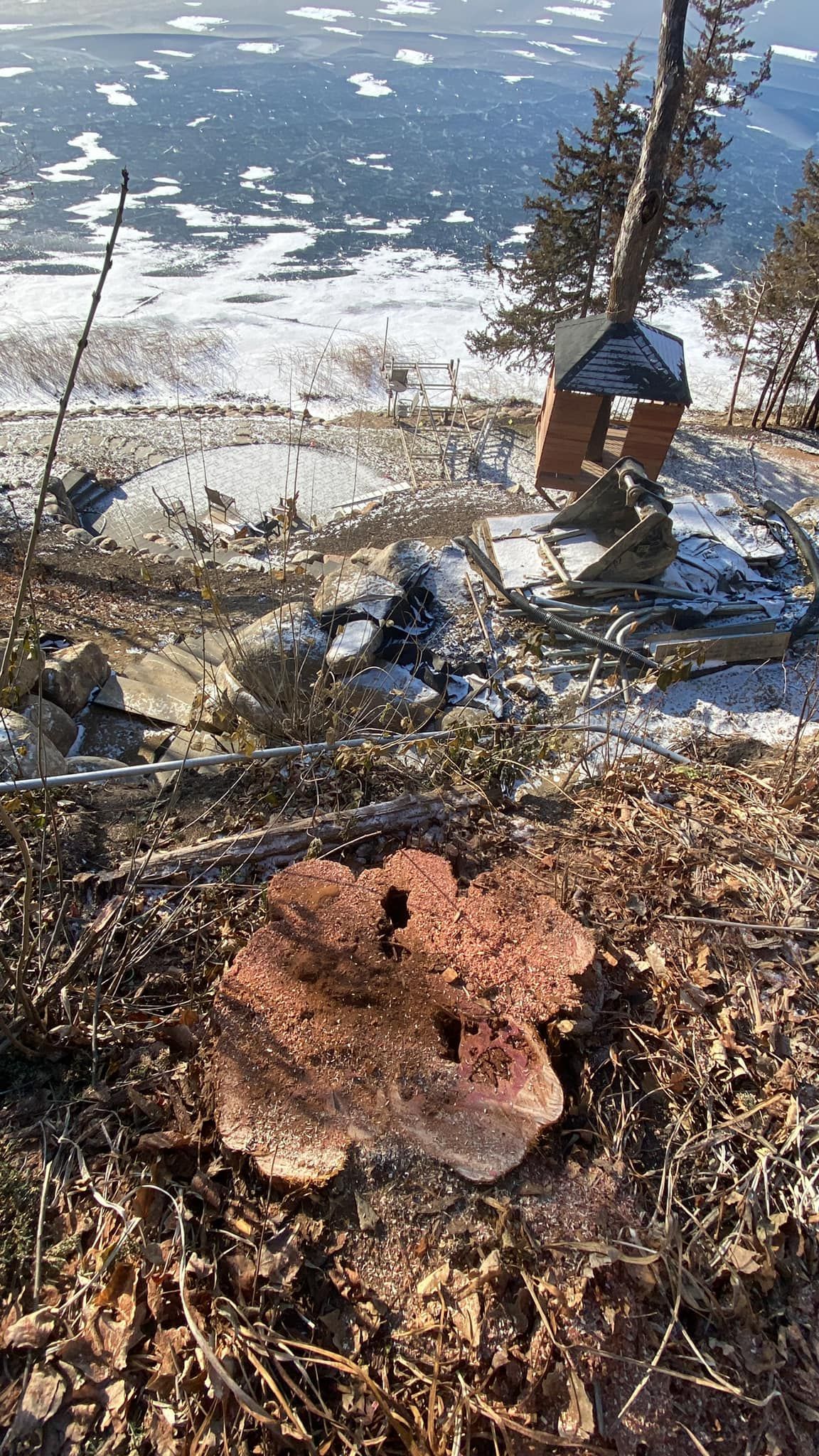 Brown, porous rock in foreground, snow-covered hill with a partially frozen lake in the background.