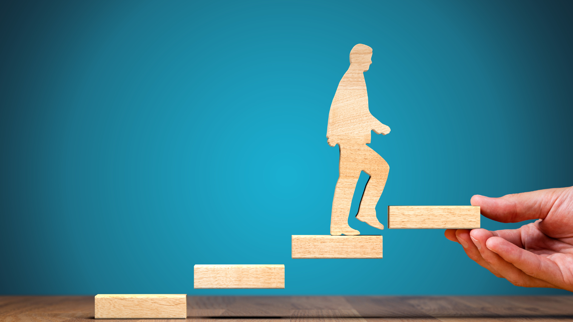 Eine Person hält einen Holzblock mit der Silhouette eines Mannes, der die Treppe hinaufgeht.