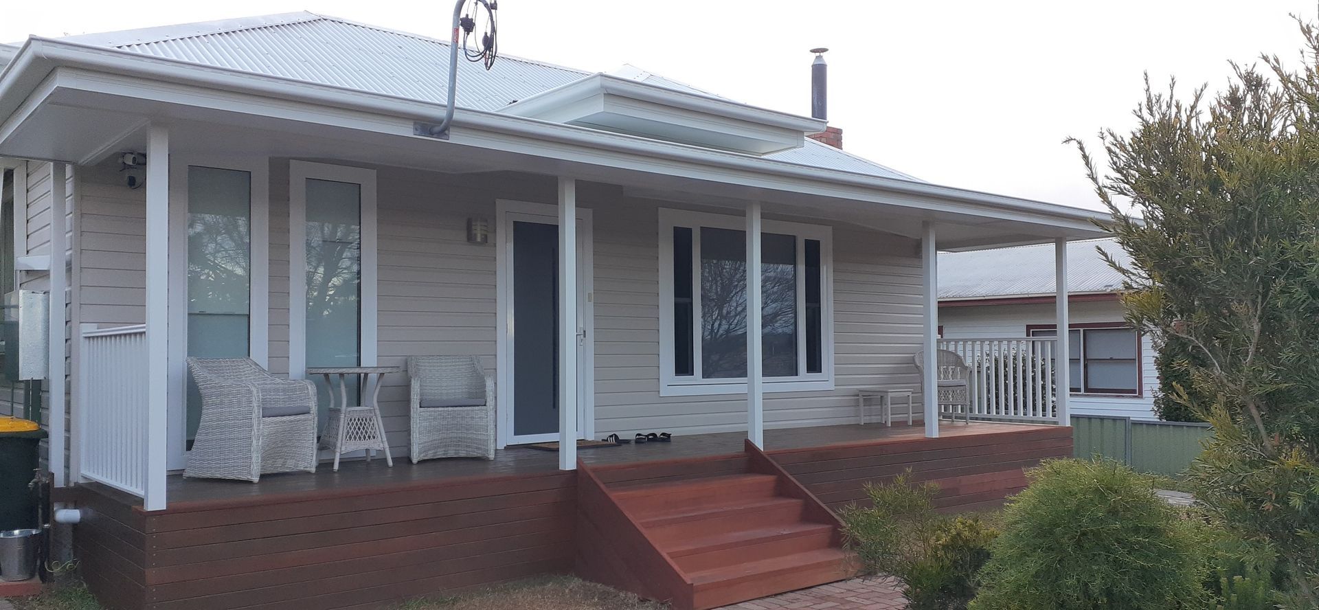 A white house with a porch and chairs on it.