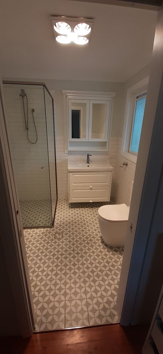 A bathroom with a toilet , sink , shower and mirror.