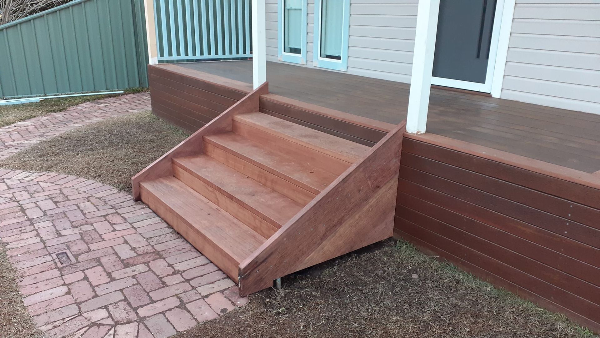 A wooden staircase leading up to a porch of a house.