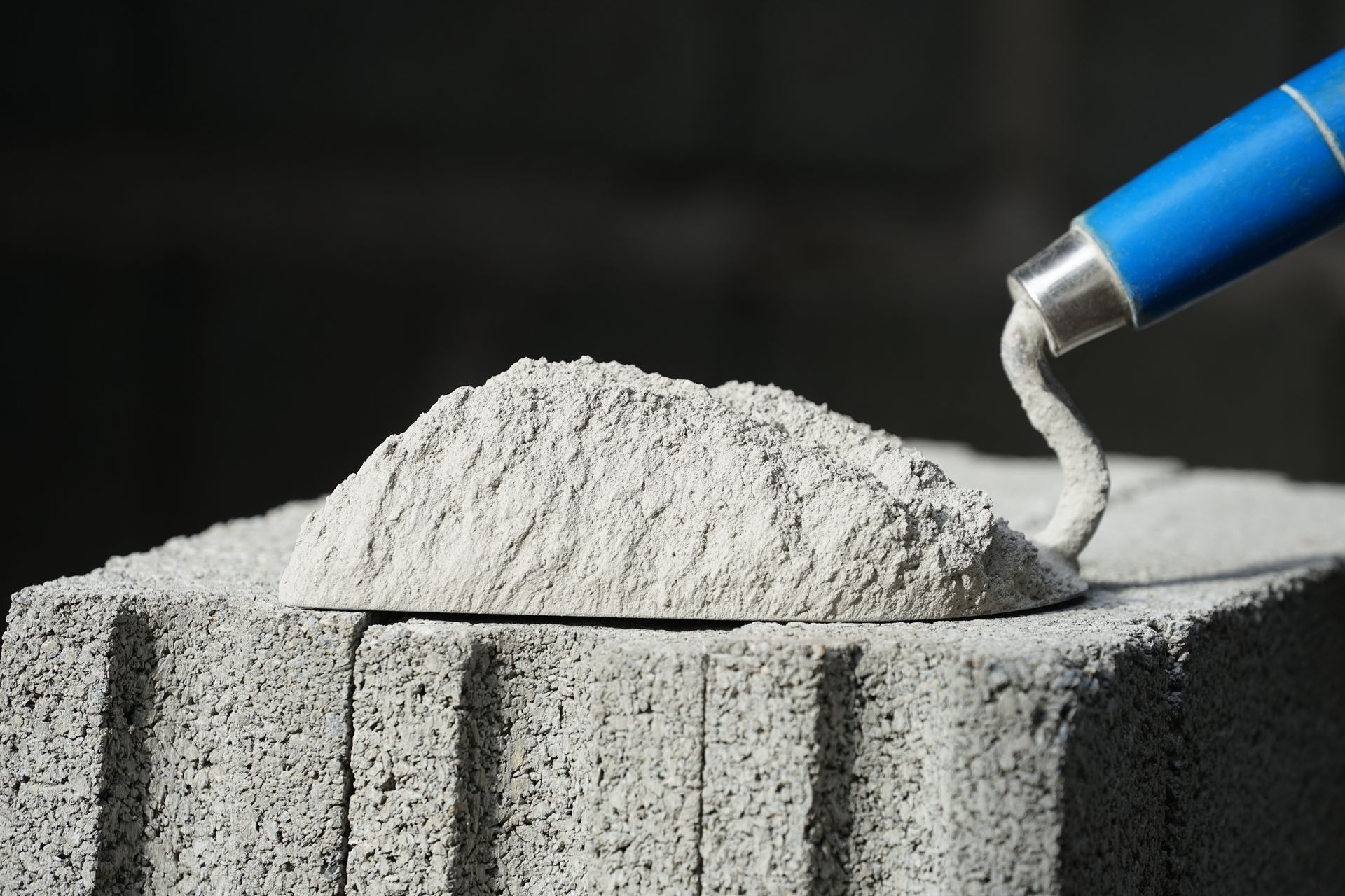 Una persona sta versando cemento su un mattone con una cazzuola.