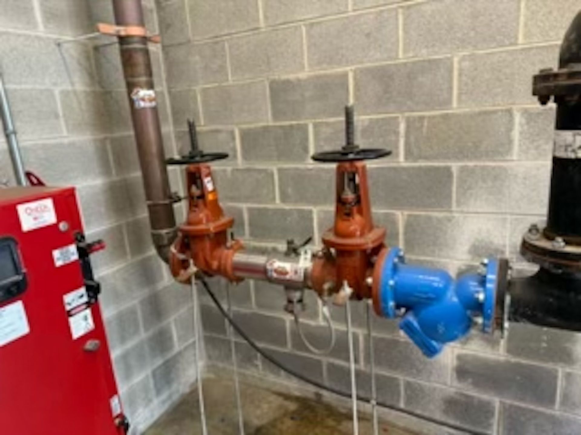 A room with a red box and a bunch of pipes and valves