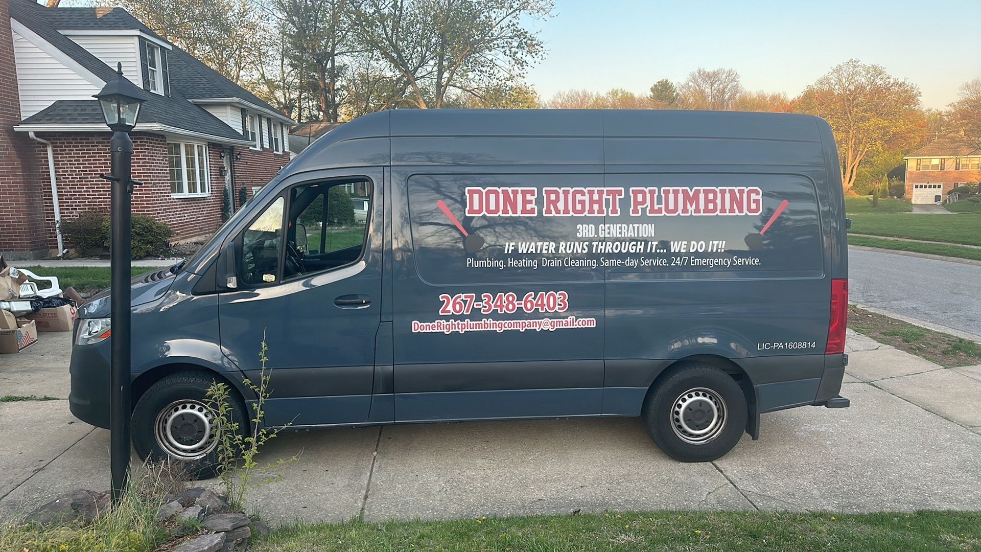 A black van is parked in a driveway in front of a house.