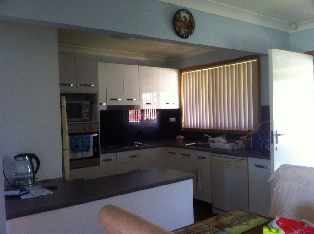 A Kitchen With White Cabinets And A Clock On The Wall — Standfast Cabinets In Tuggerah, NSW