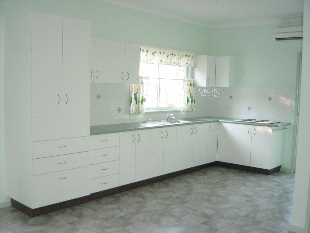 An Empty Kitchen With White Cabinets And A Window — Standfast Cabinets In Tuggerah, NSW