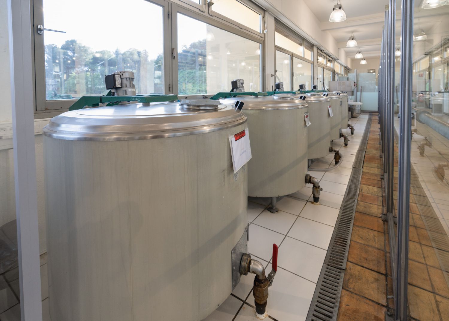 A row of stainless steel tanks from Boiler Technologies Unlimited are lined up in a room.