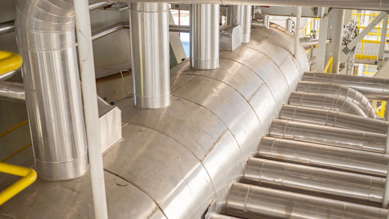 A bunch of metal pipes are connected to each other in a factory.