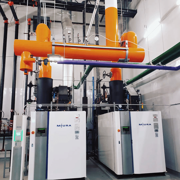 A Miura modular industrial boiler with a white casing, metallic front panel, and black mechanical components on top.