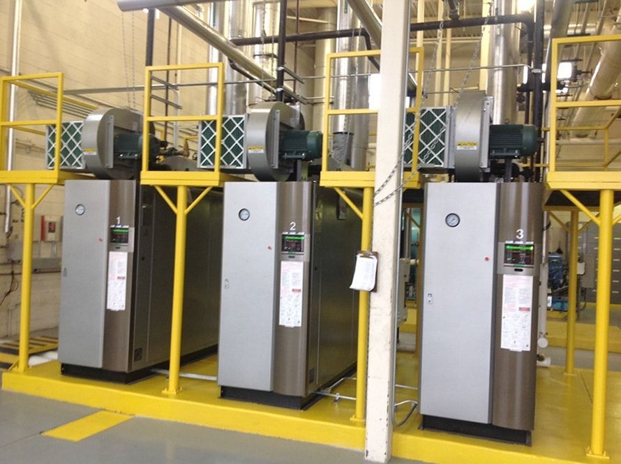 Row of industrial HVAC units in a yellow-railed mechanical room