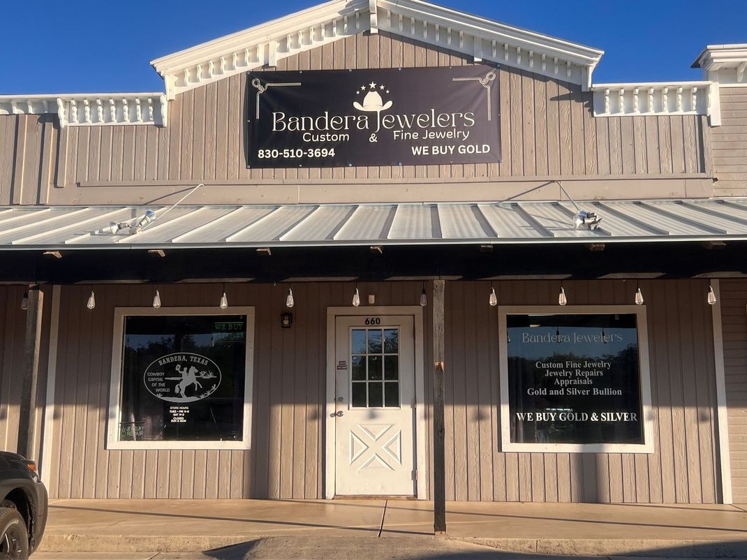 Gold bracelet with two diamond-like flower designs on a black background.