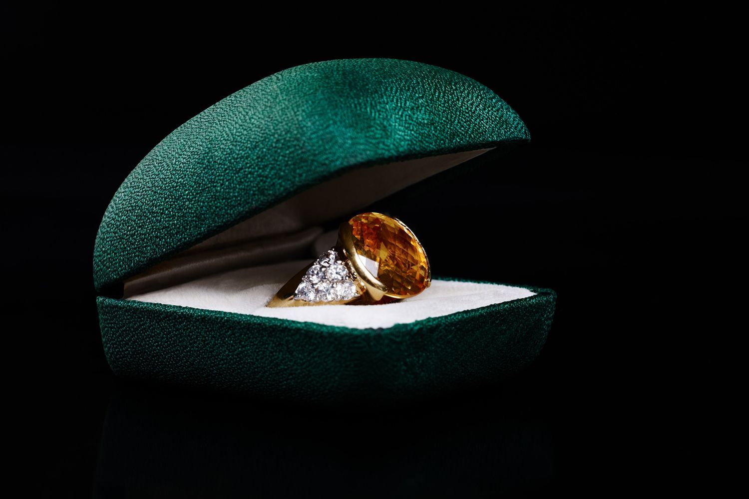 Ring in a green velvet box against a black background.