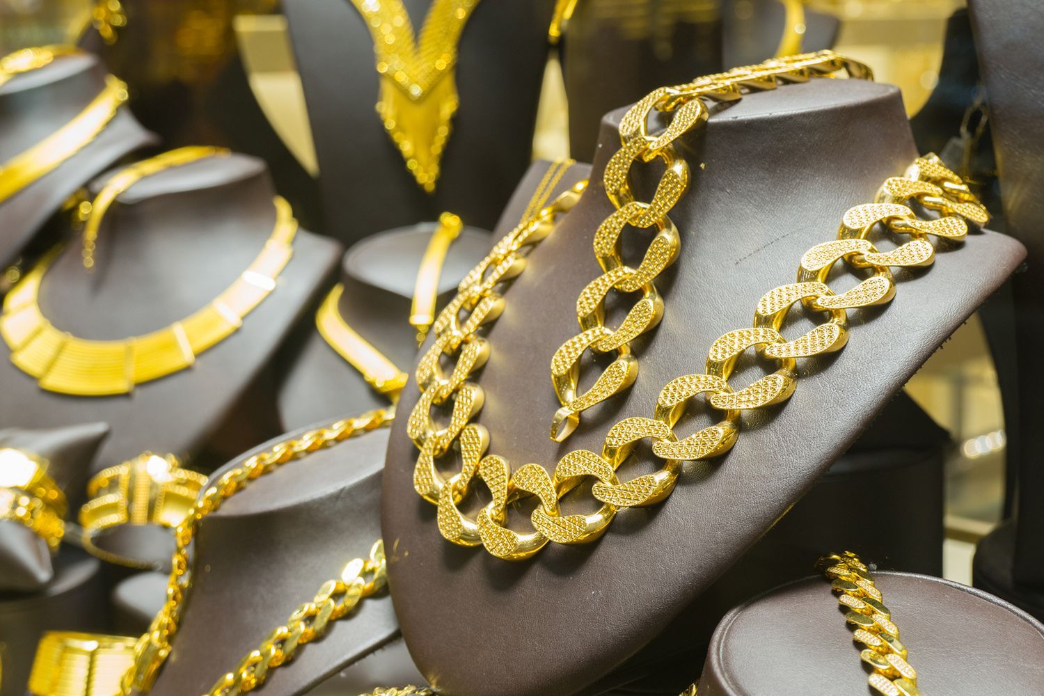 Gold necklaces displayed on dark jewelry busts.
