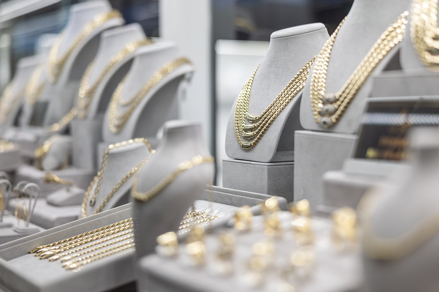 Golden necklaces and rings displayed on jewelry store mannequins.