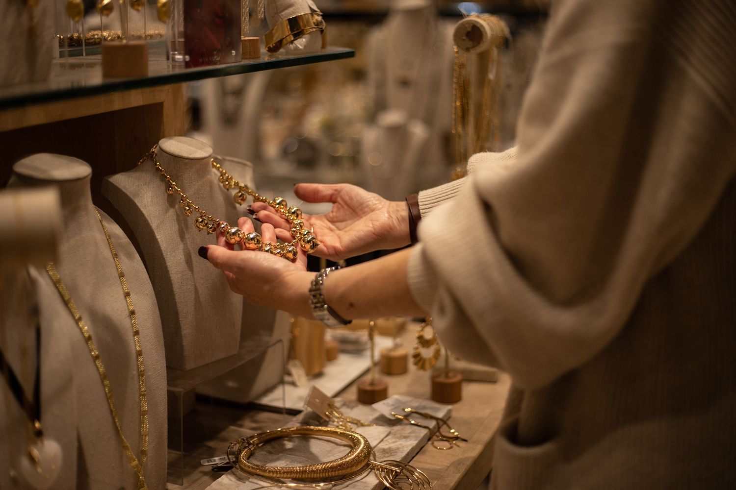 Woman examining a gold necklace in a jewelry store.