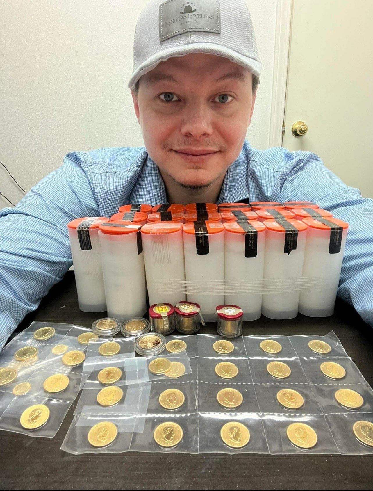 Jewelry display: gold ring, necklaces with pearls and pendants, heart brooch, all on dark surface.