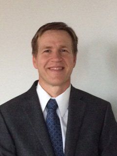 A man in a suit and tie is smiling for the camera