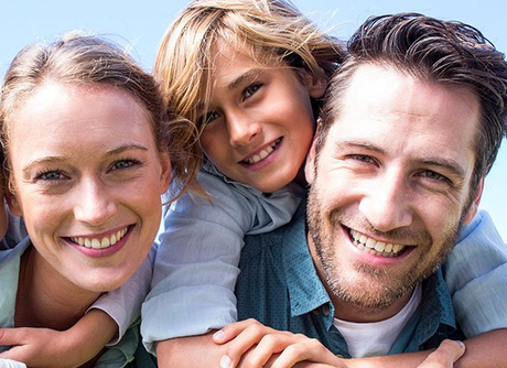 A man , woman and child are smiling for the camera.