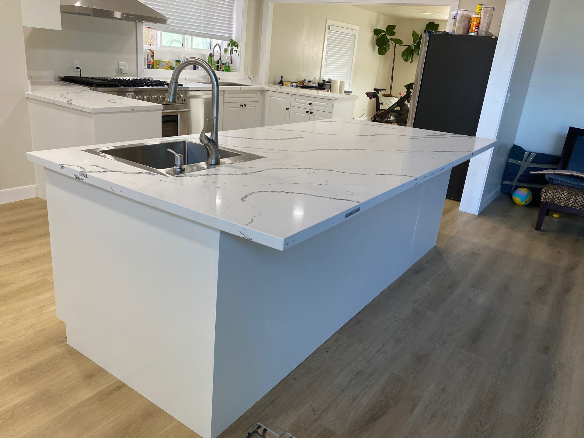 Modern kitchen with a large white island, sink, and wood-look flooring