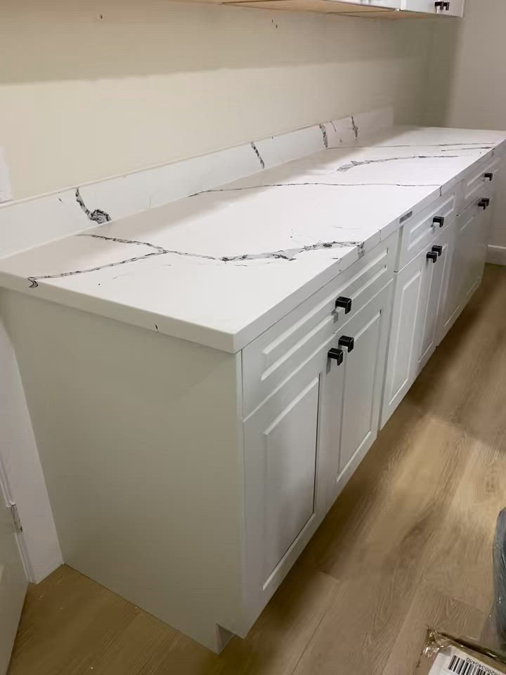 White cabinets and countertops along a wall in a bright utility or lab room.