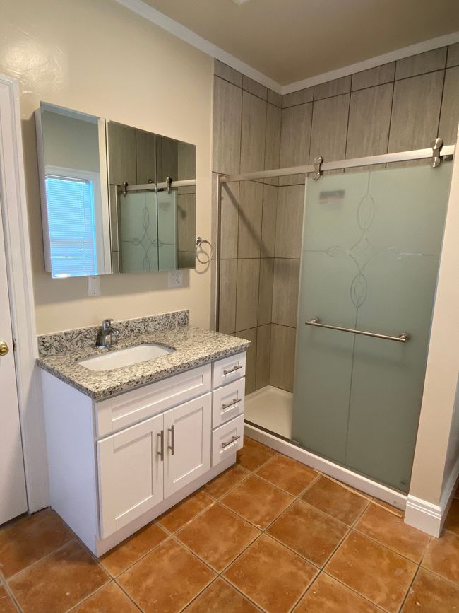 Bright marble bathroom with double vanity, large mirrors, and glass-enclosed shower