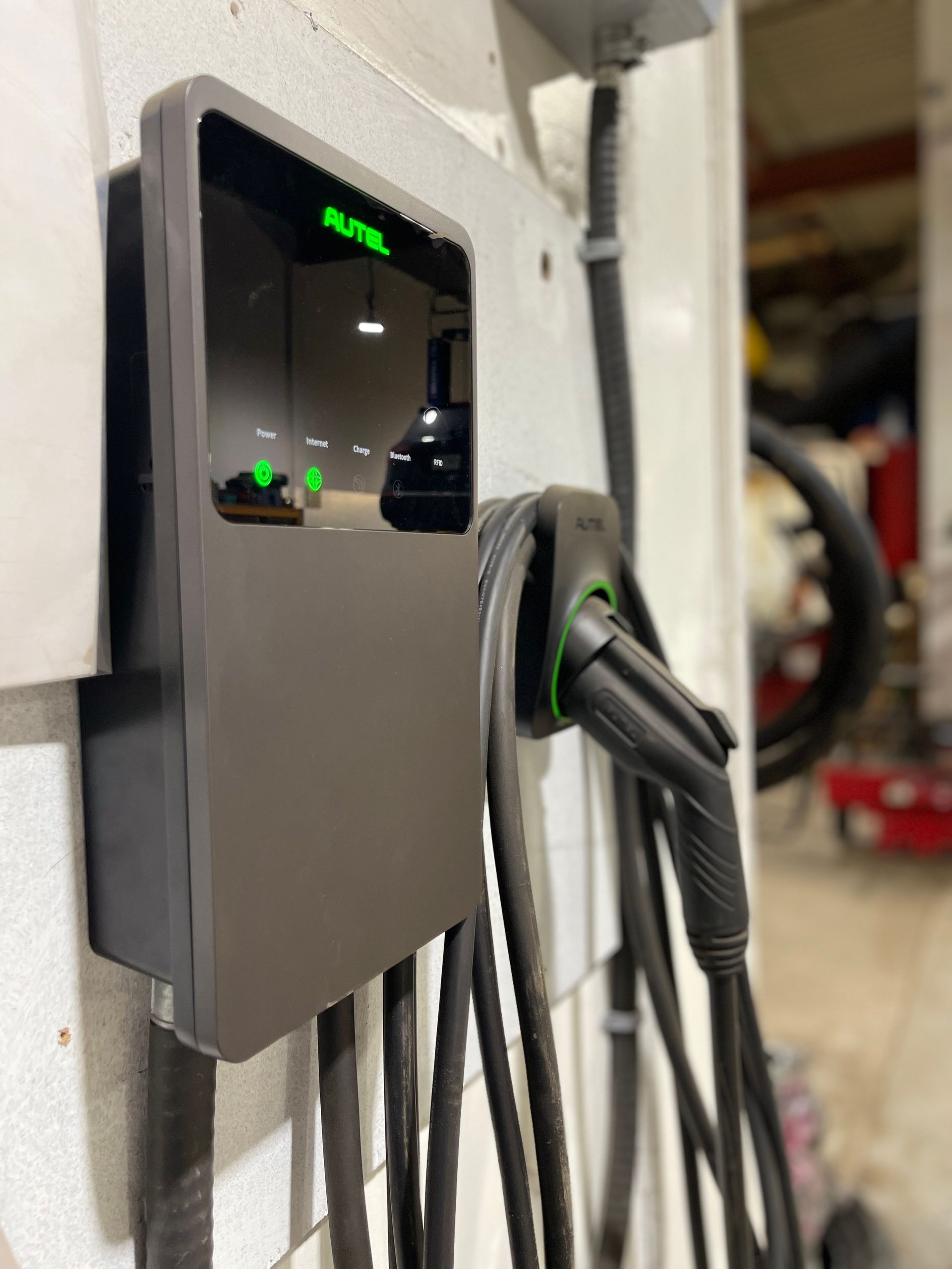 A charging station for an electric car is hanging on a wall.