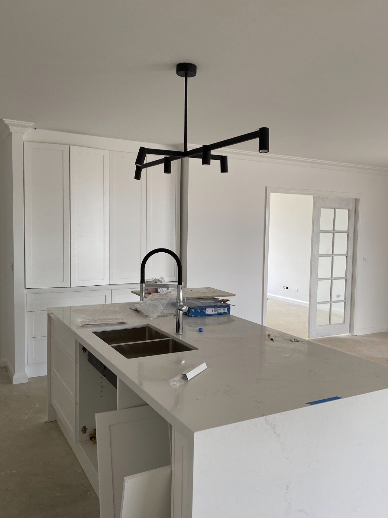 Modern kitchen with white cabinets, island, black faucet, and a black chandelier.