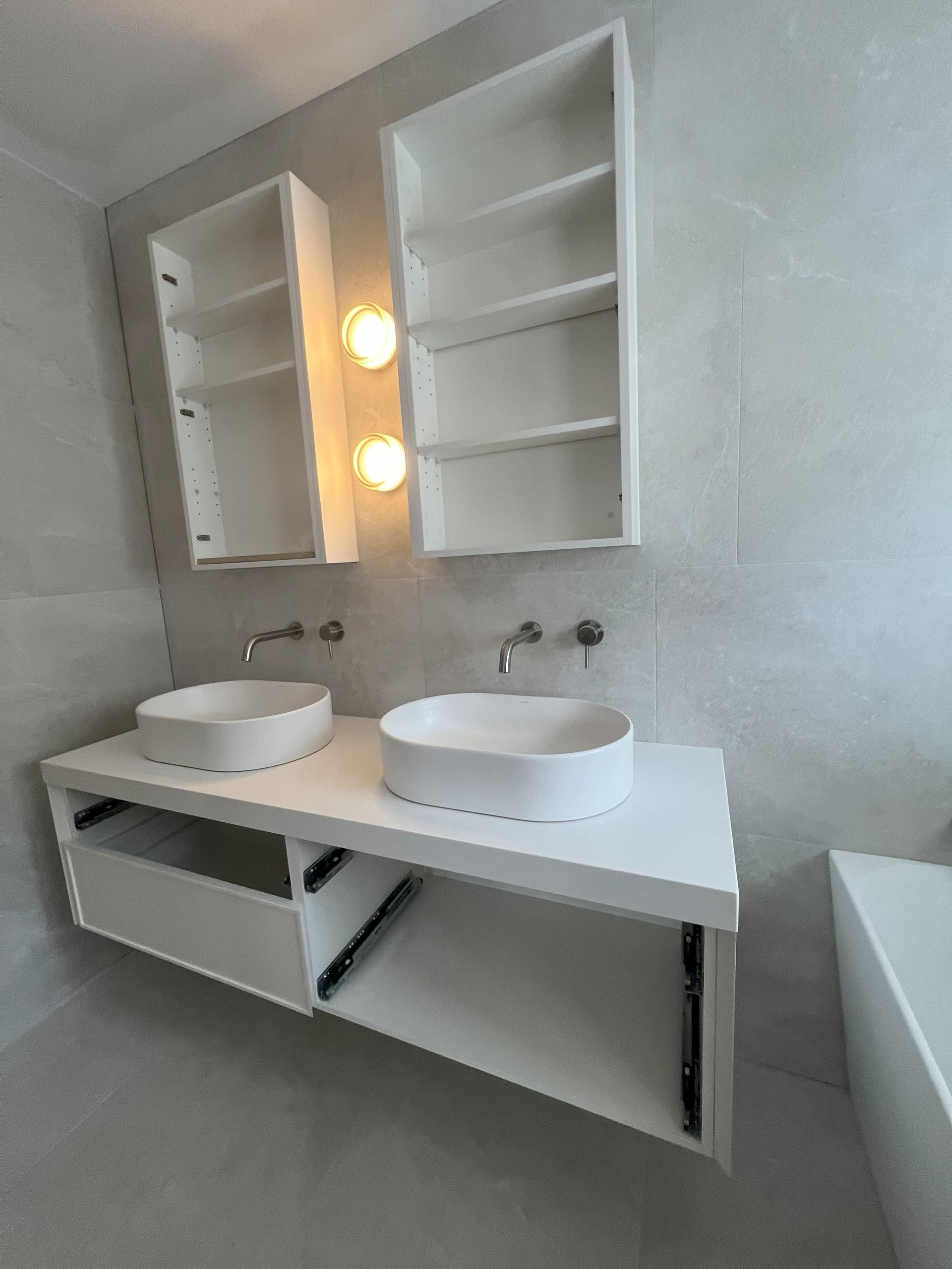 White double sink vanity with matching cabinets and sconces in a modern bathroom.