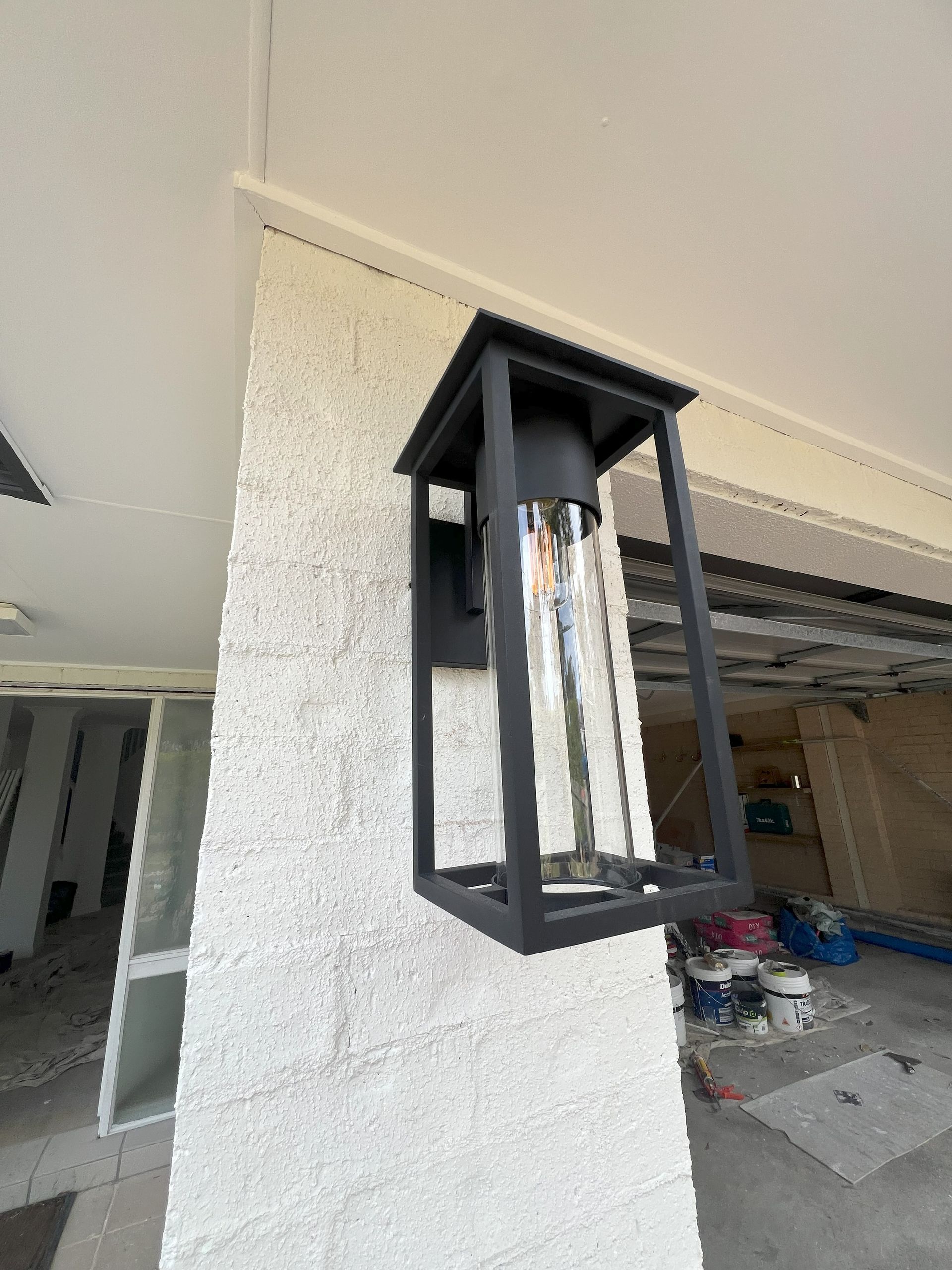 Black outdoor lantern mounted on a stucco wall.