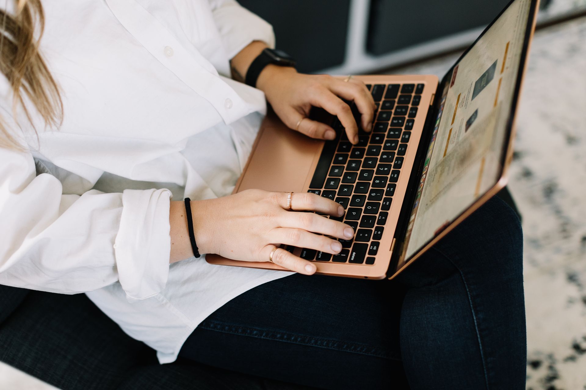 A woman is sitting on a couch using a laptop computer.