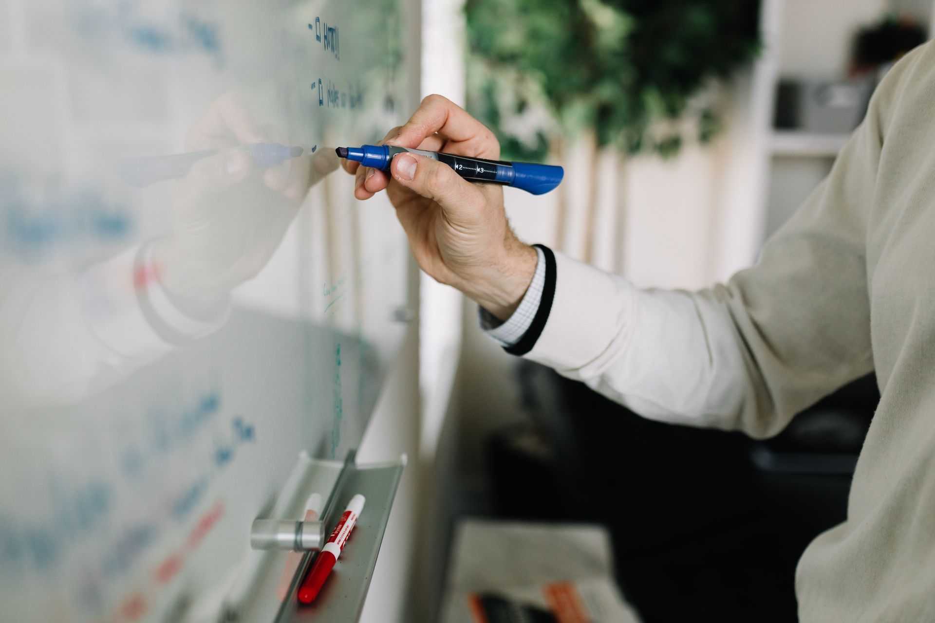 A person is writing on a whiteboard with a marker.