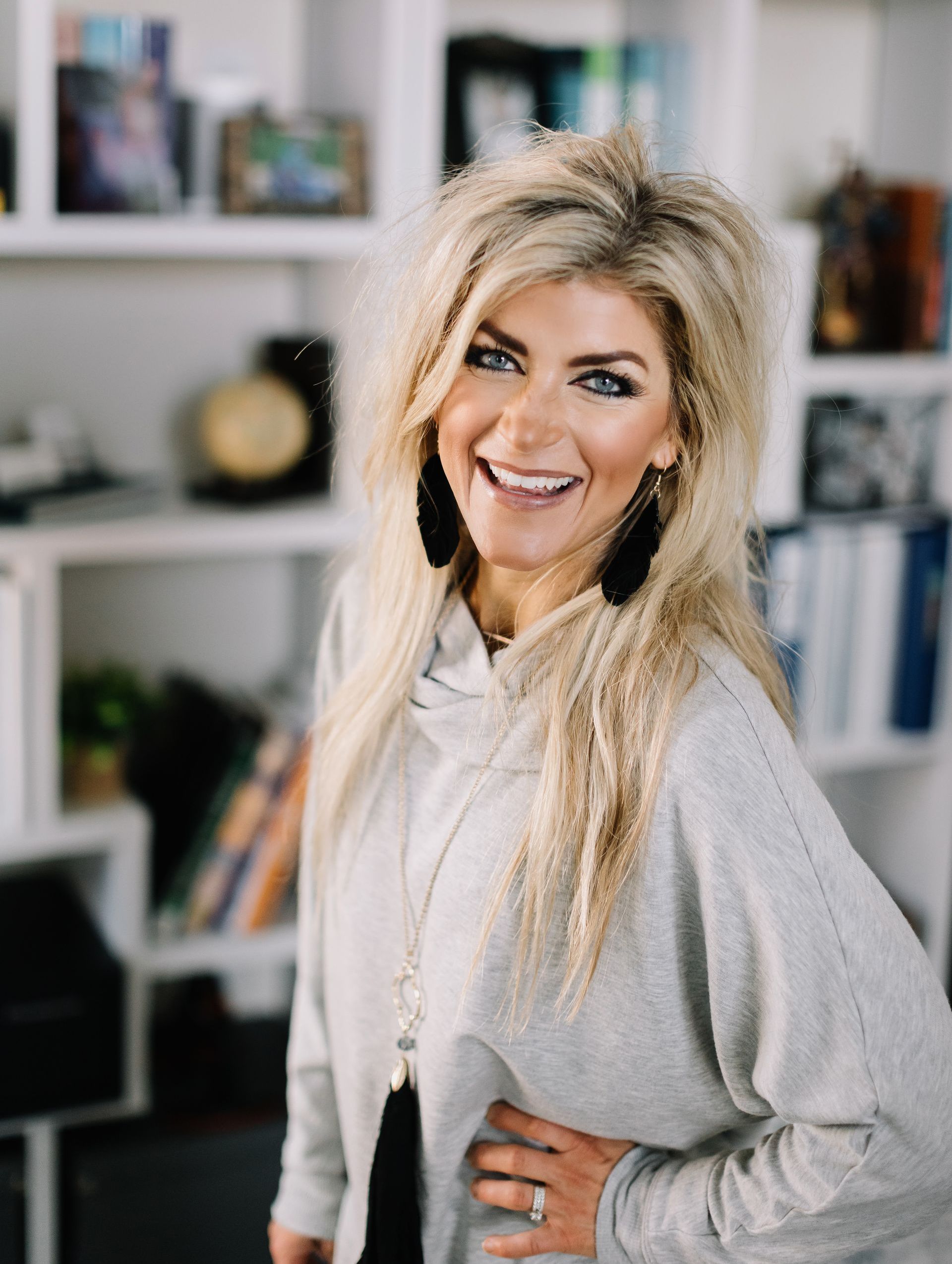 Kristine KNight photo -A woman is standing in front of a bookshelf and smiling.