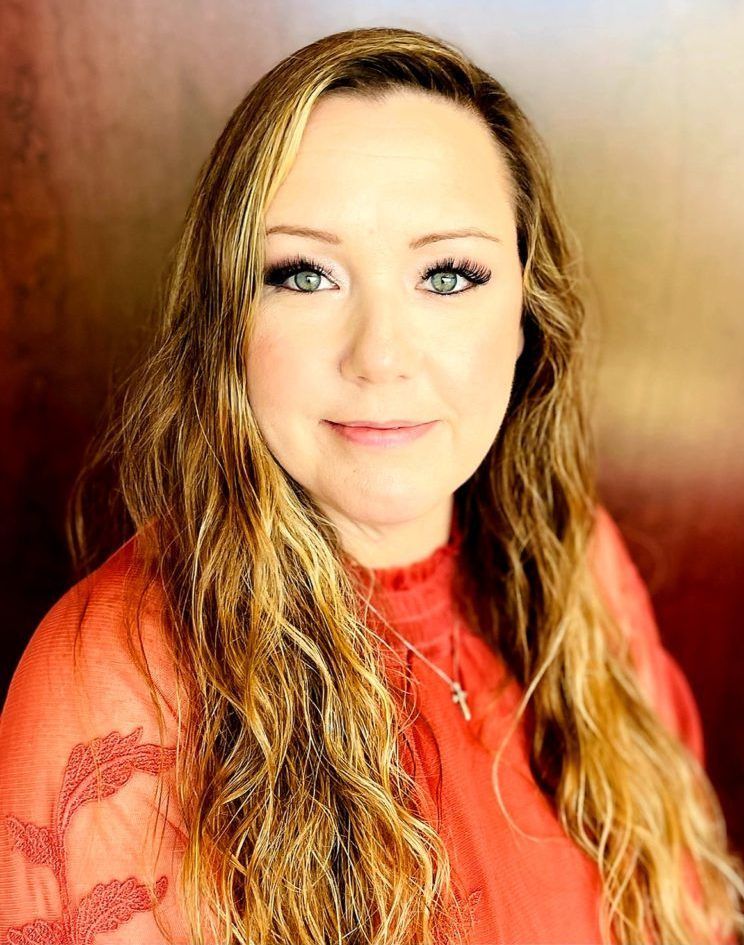 Donna Venegoni photo - A woman with long blonde hair is wearing a red shirt and a cross necklace.