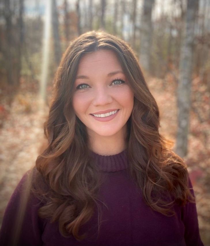 Kelli Gray photo - The woman is wearing a purple sweater and smiling for the camera.