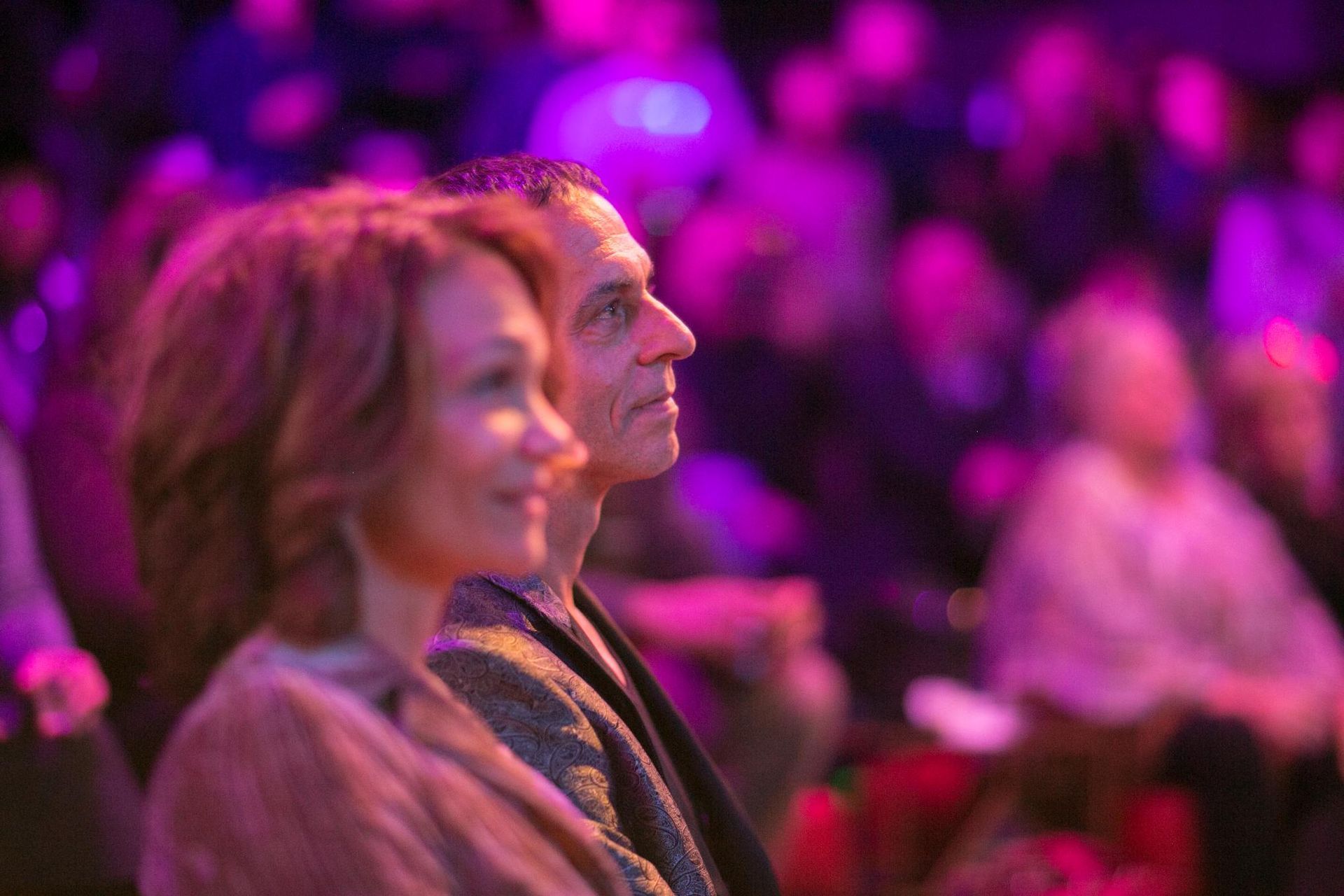 A man and a woman are sitting in front of a crowd at a concert.