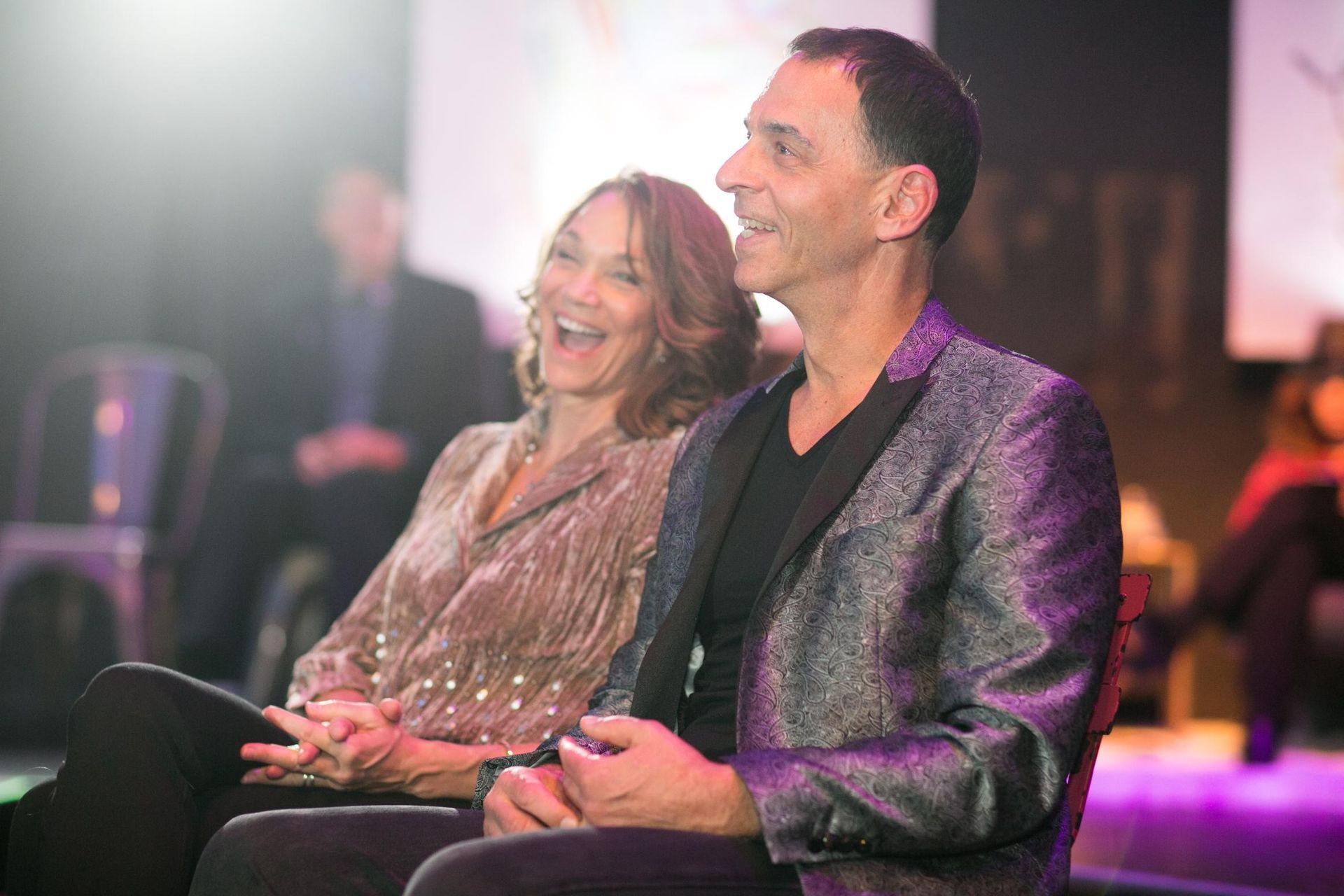 A man and a woman are sitting next to each other and laughing.