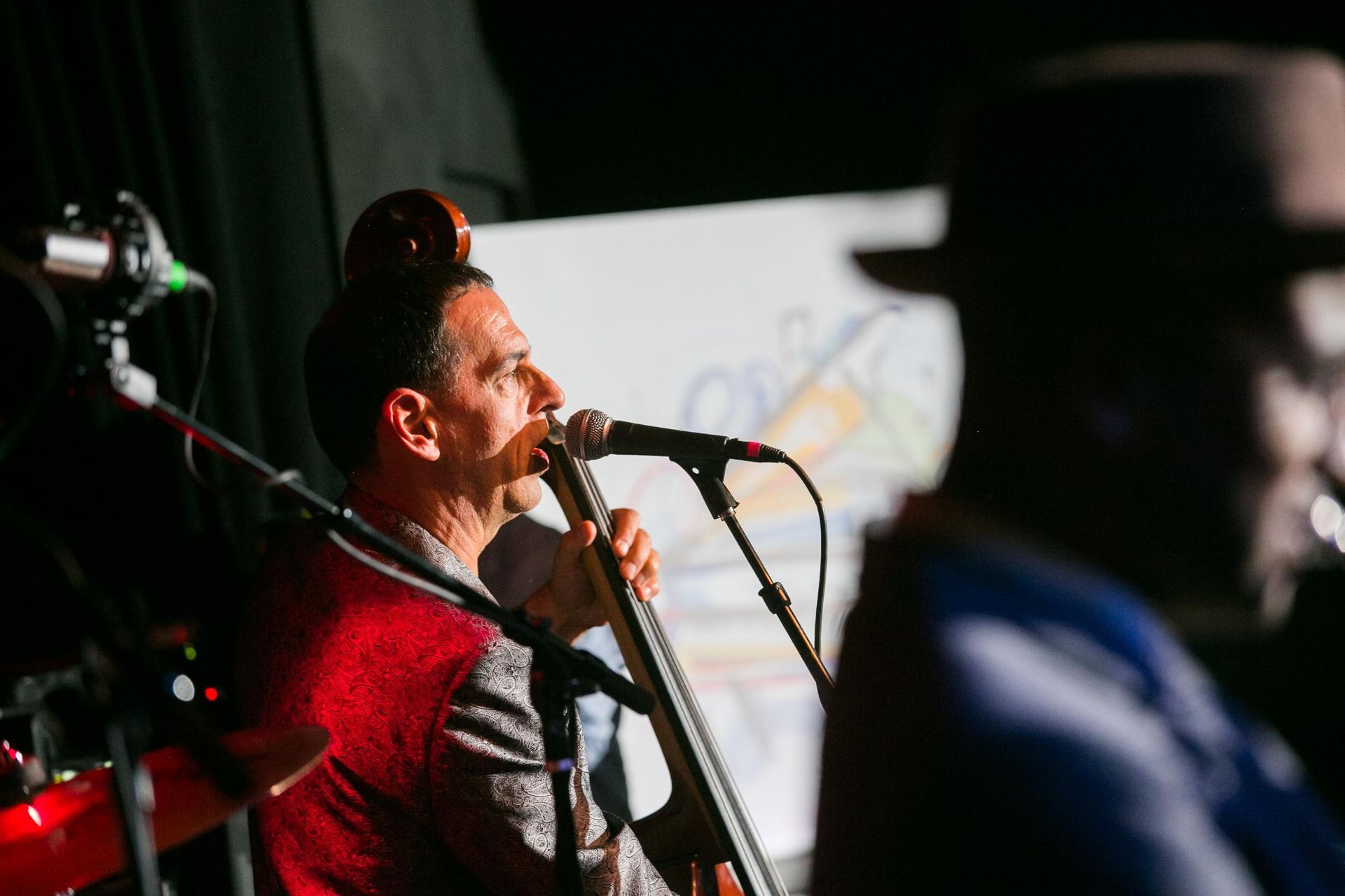 A man is singing into a microphone while playing a cello.