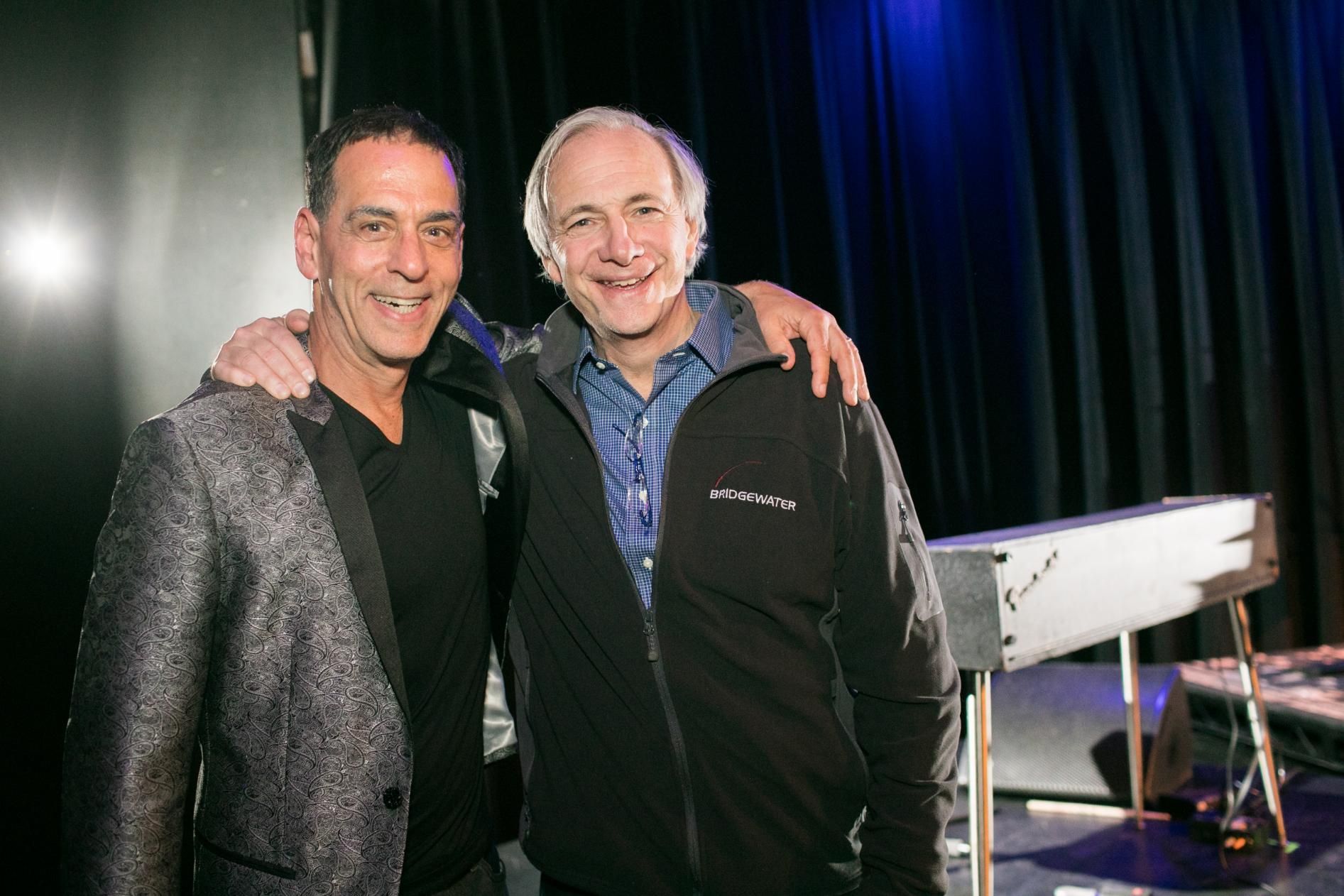 Two men are posing for a picture in front of a piano.