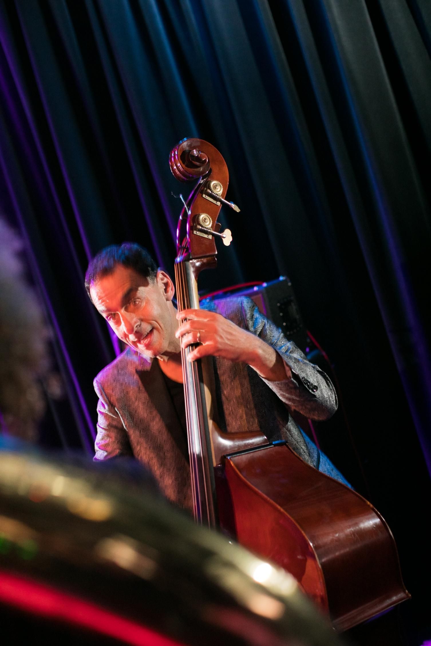 A man is playing a double bass on a stage.